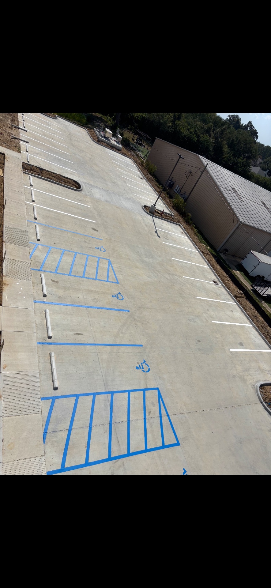 New concrete parking lot with white stalls and multiple blue accessible spaces